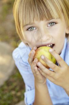 Young girl eating apple outdoors
