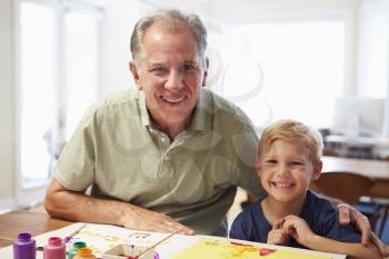 Grandfather Painting Picture With Grandson At Home