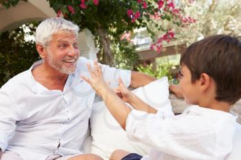 Grandfather At Home Sitting On Outdoor Seat With Grandson