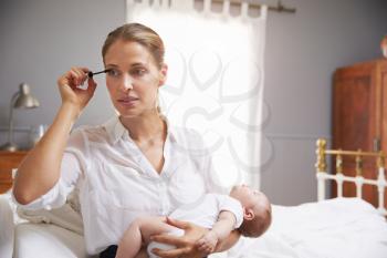 Working Mother Holding Baby And Putting On Make Up