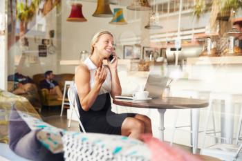 Businesswoman using phone in a coffee shop