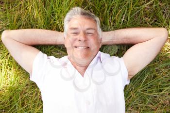 Senior man lying on grass relaxing