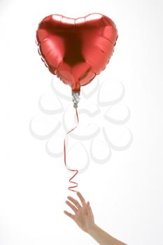 Hand Letting Go Of Heart Shaped Balloon On White Background