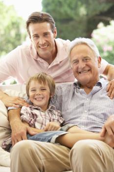 Grandfather With Son And Grandson Laughing Together On Sofa