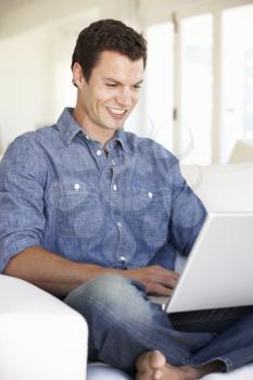 Young Man Using Laptop Computer At Home
