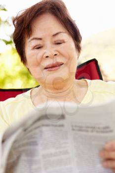 Senior Asian woman reading outdoors