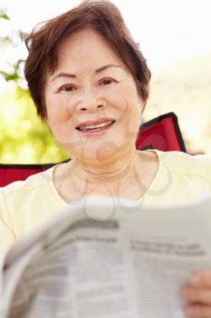 Senior Asian woman reading outdoors