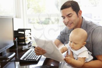 Hispanic father with baby working in home office