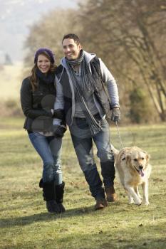Couple walking golden retriever in the country