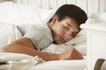 Teenage Boy Asleep In Bed At Home