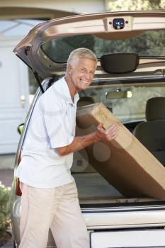 Senior Man Loading Large Package Into Back Of Car