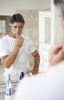 Man Brushing Teeth In Bathroom Mirror