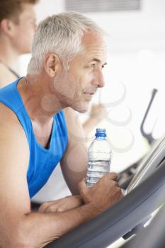 Man On Running Machine In Gym Drinking Water