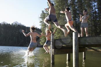 Group Of Young People Jumping From Jetty Into Lake
