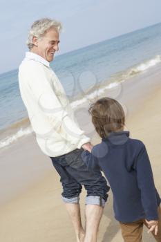 Grandfather And Grandson Walking Along Beach