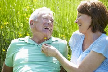 Senior Couple Relaxing In Summer Field Together