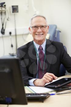 Male Consultant Working At Desk Using Digital Tablet