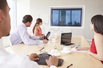 Four Businesspeople Having Video Conference In Boardroom