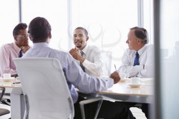 Four Businessmen Having Meeting Around Boardroom Table