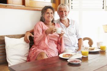 Portrait Of Mature Couple Sitting At Breakfast Table