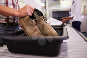 Man Putting Shoes Into Tray For Airport Security Check