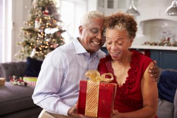 Senior Couple Exchanging Christmas Gifts At Home