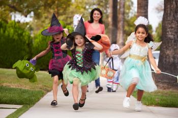 Parent Taking Children Trick Or Treating At Halloween