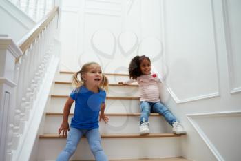 Two Girls Playing Game On Staircase At Home