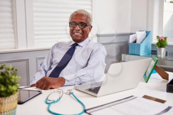 Senior black male doctor in an office looking to camera