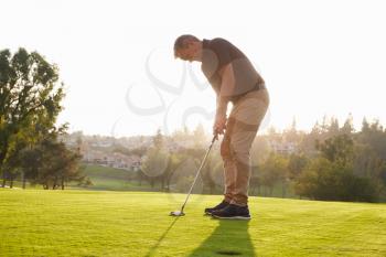 Male Golfer Lining Up Putt On Green
