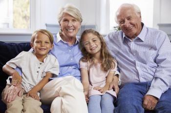 Portrait Of Grandparents And Grandchildren Sitting On Sofa