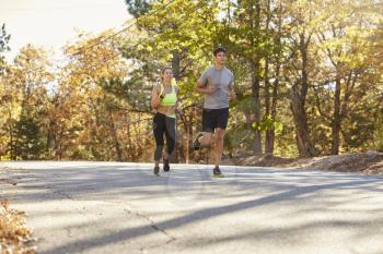 Woman and man jogging on a country road, mid distance