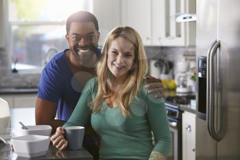 Portrait of mixed race couple in kitchen, man leaning down