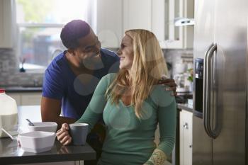Mixed race couple in kitchen look closely at each other