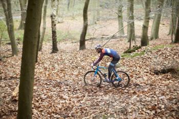 Young man cross-country cycling through a forest