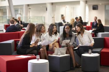 Businesswomen Meeting In Busy Lobby Of Modern Office