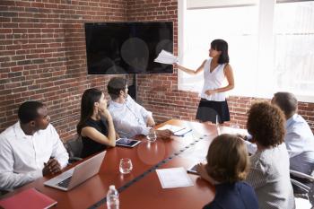 Businesswoman Addressing Boardroom Meeting With Screen