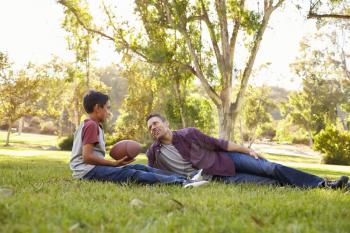 Father and son with football relaxing in a park
