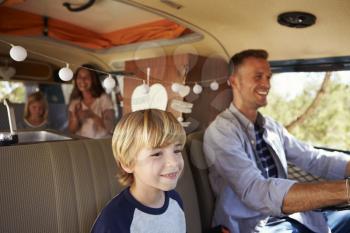 Dad driving family in a camper van, with son up front