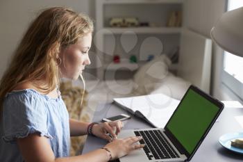 Teenage girl using laptop at a desk in her bedroom, close up