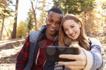 Smiling mixed race couple take a selfie in a forest