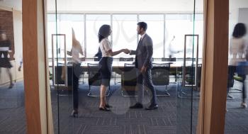 Businesspeople Shaking Hands In Entrance To Boardroom