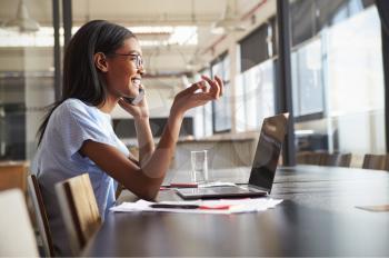 Young black woman in office talking on smartphone