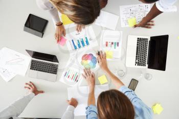 Desk and colleagues at a business brainstorm, overhead view