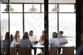 Team in a business boardroom meeting seen through glass wall