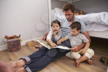 Father Reading Story To Children In Their Bedroom