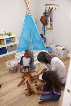 Mother And Children Playing With Building Blocks In Bedroom