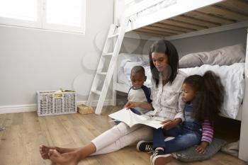 Mother Reading Story To Children In Their Bedroom