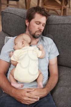 Tired Father With Baby Son Sleeping On Sofa Together