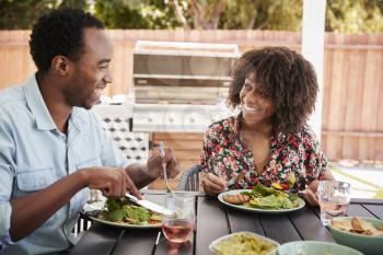 Young black couple eating lunch at a table in the garden